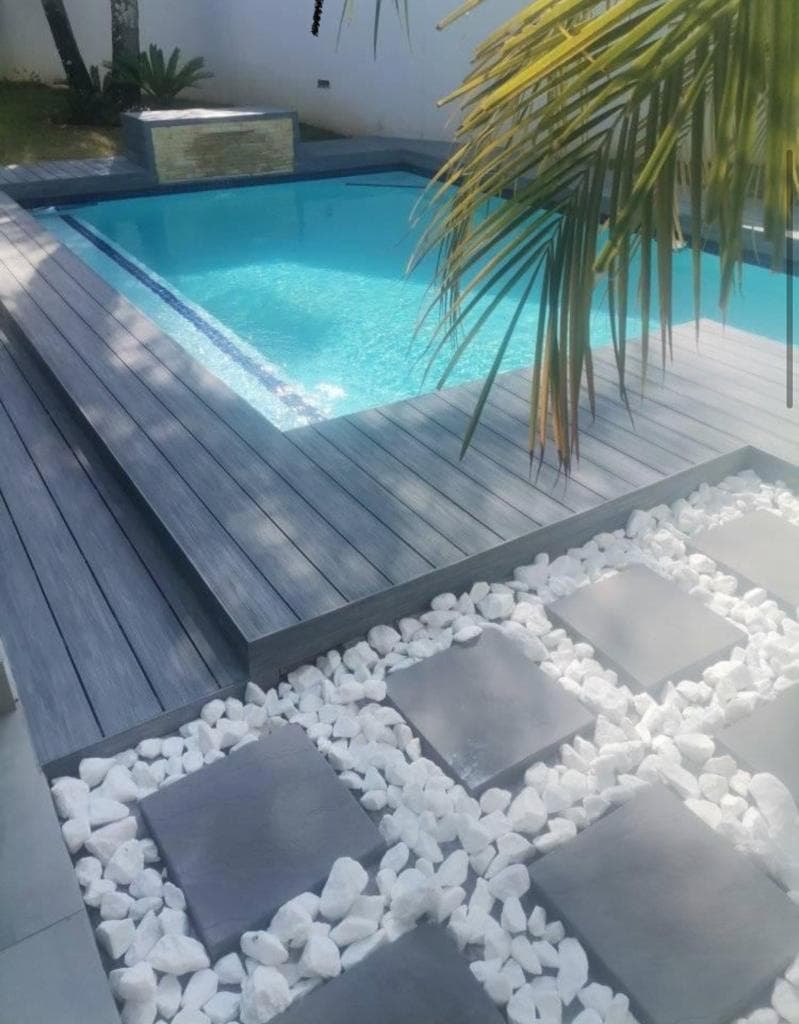 Composite deck surrounding a swimming pool with white pebble garden in Centurion